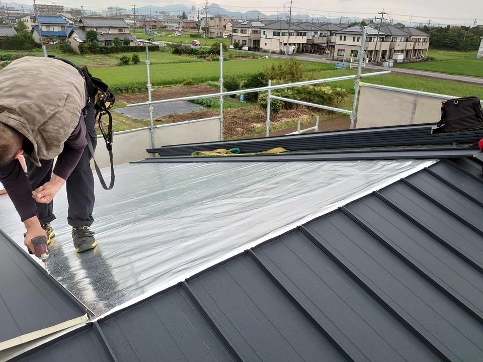 住宅の屋根に遮熱シート施工中の事例画像